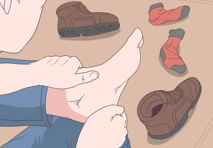 A person checks their foot, surrounded by hiking boots and socks, to prevent walking boots rubbing above the ankle.