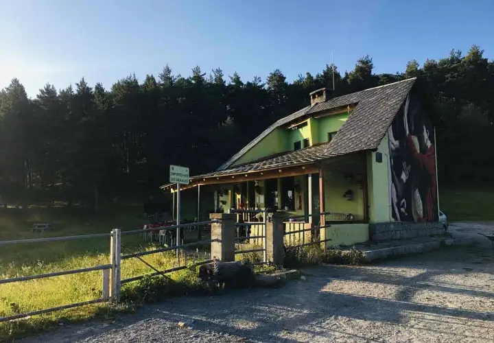 El refugi Serrat de les Esposes, un refugio acogedor rodeado de pinos, con un mural artístico en su fachada.
