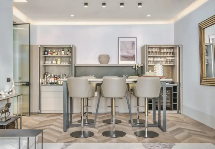 Modern bar area with sleek bar stools. The question of whether bar stools should match dining chairs is answered by this elegant setup.