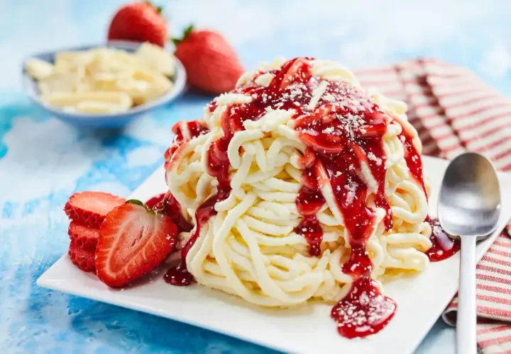 Ein köstliches Spaghetti-Eis-Dessert mit Erdbeersauce und frischen Erdbeeren, garniert mit weißer Schokolade.