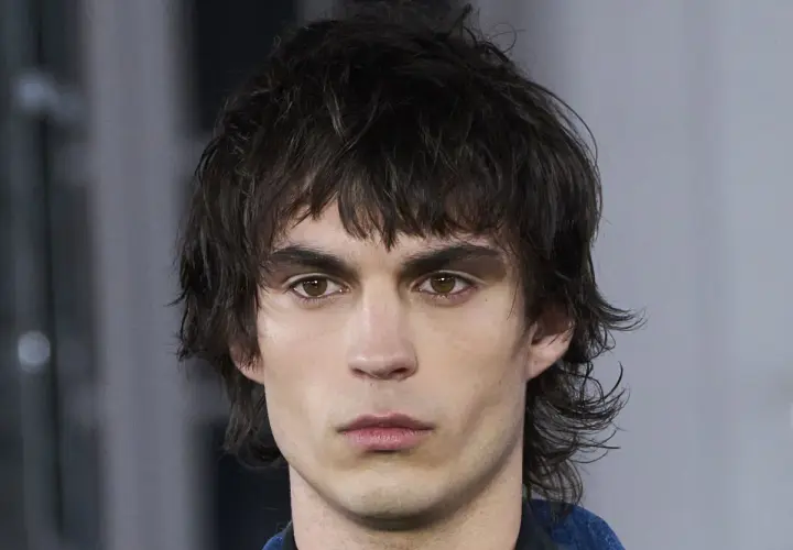 Hombre con un moderno mullet de pelo corto, mirada intensa y cejas marcadas.