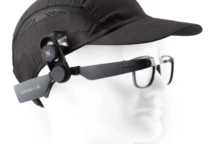 Ein schwarzer Hut mit einer Kamera, die per Vision gesteuert wird, ist an einer Brille befestigt.