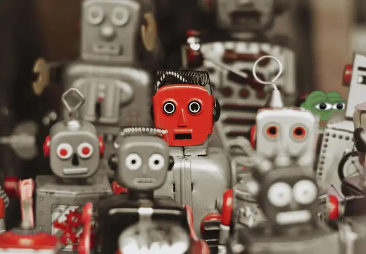 Kolekcja robotów zabawek, w tym jeden czerwony z przerażonym wyrazem twarzy, przypomina teorię martwego internetu.