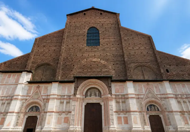 Façade imposante de la basilique San Petronio, mélange de briques rouges et de marbre blanc, sous un ciel bleu.