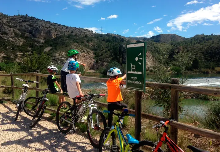 Niños en bicicleta disfrutan de la **vía verde Val de Zafán**, señalizada con un mirador panorámico.