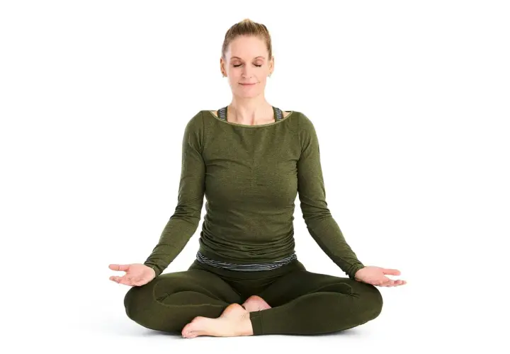 Kvinna i meditationsställning, fokuserad på breath work.