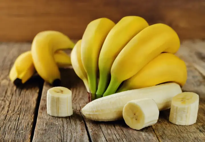 Pęczek dojrzałych bananów, jeden obrany, kilka plasterków. Idealny, duży banan kcal na zdrową przekąskę.