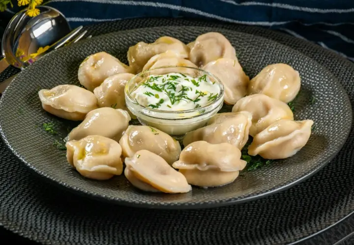 Pyszne pierogi z mięsem z rosołu, podane z gęstą śmietaną i koperkiem. Idealne na obiad.