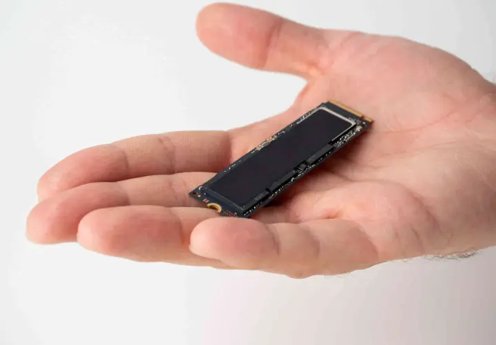 Dłoń trzyma mały dysk SSD M.2. Jego obecność zapewnia szybkie działanie systemu i optymalizację dzięki funkcji ssd trim.