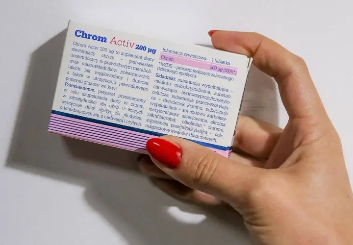 Dłoń trzyma opakowanie suplementu diety Chrom Activ 200 µg, który zawiera chrom.