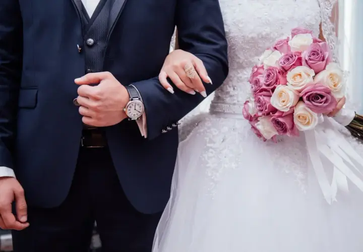 Un couple uni, main dans la main, bouquet de roses roses et blanches. Vive les mariés !
