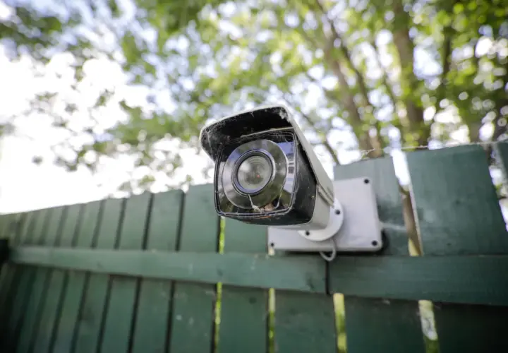 Cámara de seguridad montada en una valla verde. Ideas de camuflaje para ocultar cámaras.