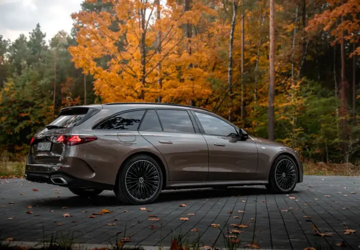 Brązowy Mercedes E300de kombi na tle jesiennego lasu.