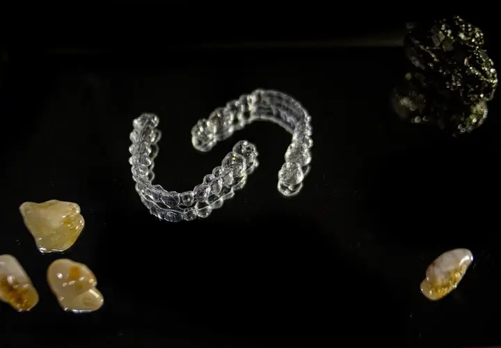 Przezroczyste nakładki Invisalign vs tradycyjny aparat ortodontyczny. Kamienie i kryształy na czarnym tle.