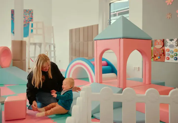 En mamma leker med sitt barn i en lekplats. En rolig och gratis upplevelse för barn i Stockholm.