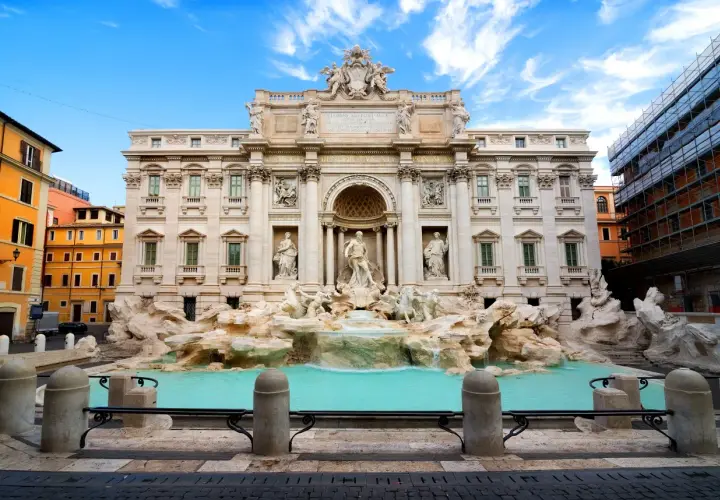 La Fontana di Trevi, con le sue sculture barocche e l'acqua turchese, incanta sotto un cielo azzurro.