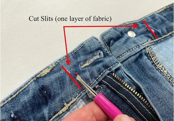 Demonstration of how to take in jeans at the waist by cutting slits in the fabric.