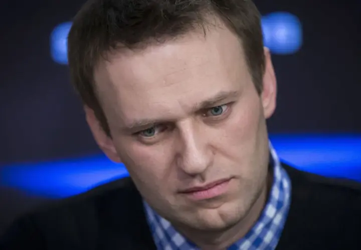 Alexei Nawalny, mit ernstem Blick und blau kariertem Hemd, im Scheinwerferlicht.