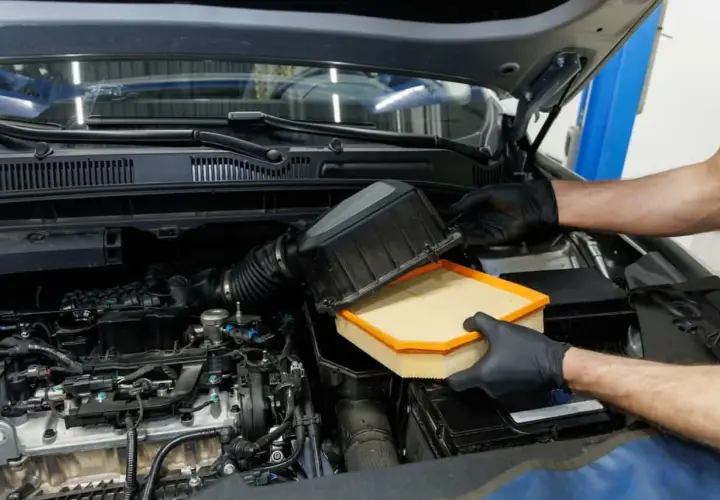 Manos enguantadas cambian el filtro del aire del coche. Este componente es vital para el motor, ya que el filtro del aire ¿para qué sirve? Limpia el aire que entra.