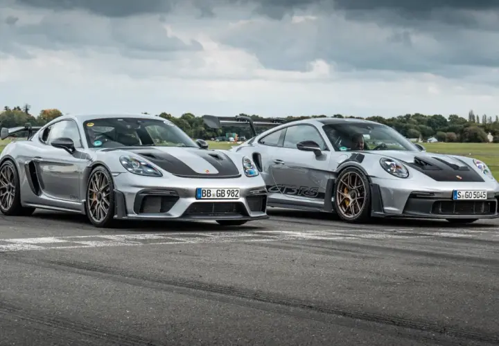 Zwei silberne Porsche GT4 und GT4 RS stehen nebeneinander auf einer Rennstrecke.