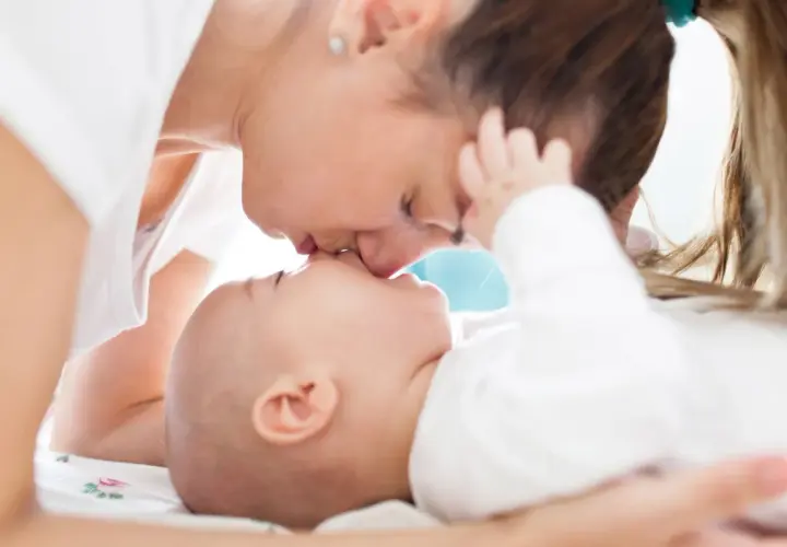 Ciepły uścisk mamy i jej 7 miesięczne dziecko. Delikatne pocałunki i miłość w spojrzeniu.
