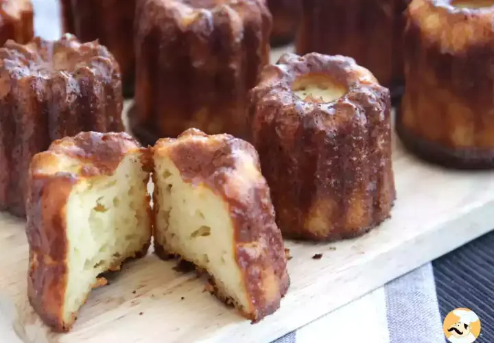 Délicieux cannelés dorés, un classique de la recette cannelés. L'un est coupé en deux, révélant sa mie moelleuse.