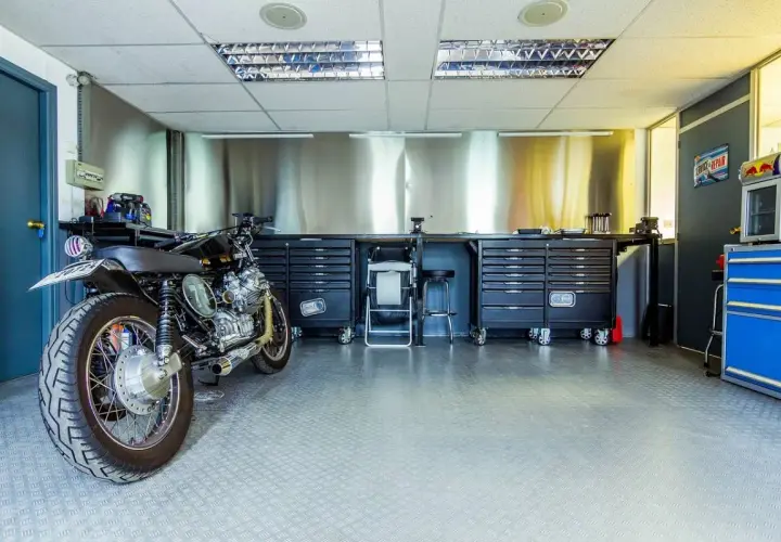 Garage per moto fai da te con moto custom, banchi da lavoro, cassettiere e attrezzi.
