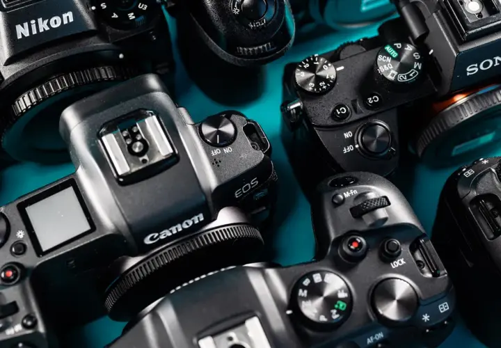 Kolekcja aparatów cyfrowych marek Nikon, Canon i Sony. Widać detale obudów, pokrętła trybów i logo, świadczące o bogatej historii marki dawnych aparatów fotograficznych.