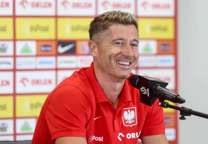 Uśmiechnięty Robert Lewandowski w czerwonej koszulce reprezentacji Polski, przed mikrofonem. Ile języków zna Robert Lewandowski?