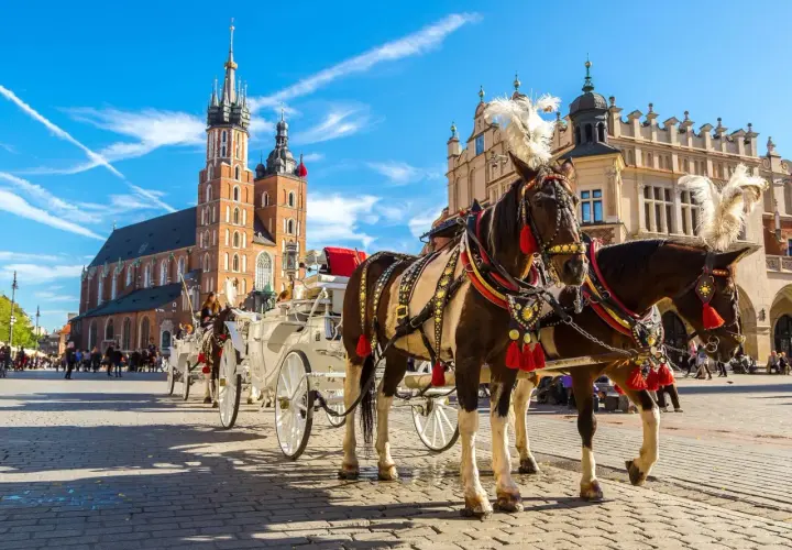 Kraków, Rynek Główny z dorożkami i Kościołem Mariackim. Zastanawiasz się, ile kosztuje nocleg w Krakowie?