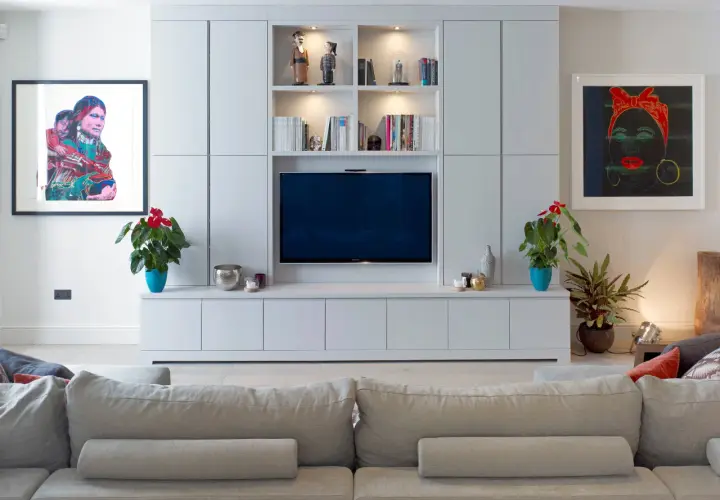 Modernt tv-rum med en stor mediabänk, konstverk och bekväm soffa.