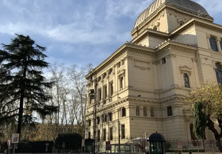 Grande Sinagoga e alberi nel quartiere ebraico di Roma, sotto un cielo azzurro con nuvole.