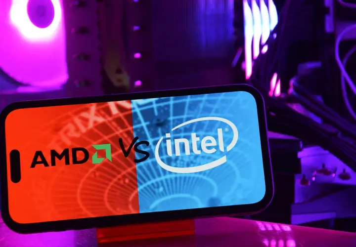 Telefon z logo AMD vs Intel na tle podświetlanego komputera. Wybór między procesorem Intel czy AMD.
