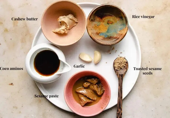 Ingredients for a delicious sesame sauce for hot pot: cashew butter, coco aminos, sesame paste, garlic, rice vinegar, and toasted sesame seeds.