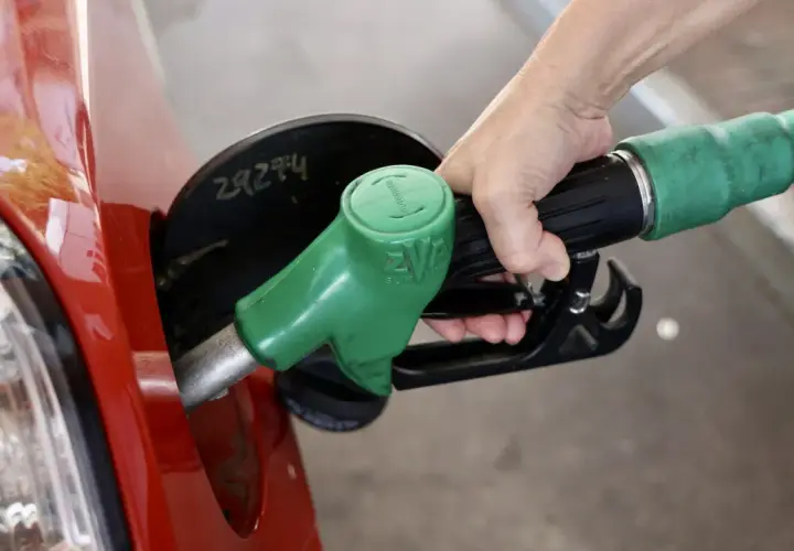 Mano repostando un coche rojo con una manguera de combustible verde. El futuro de los coches diésel aún depende de la gasolina.