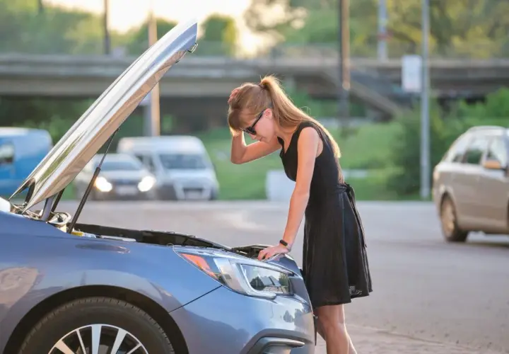 Donna preoccupata guarda il motore della sua auto, il motore diesel gira ma non parte.