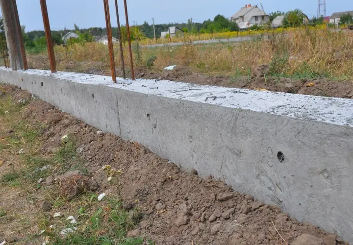 Nowy betonowy fundament z wystającymi prętami zbrojeniowymi, gotowy do połączenia ze starym fundamentem.