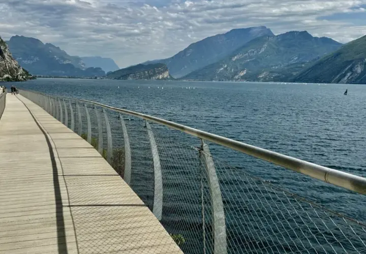 Drewniana promenada nad jeziorem Garda, z widokiem na góry i żaglówki. Idealne miejsce na spacer po mieście.