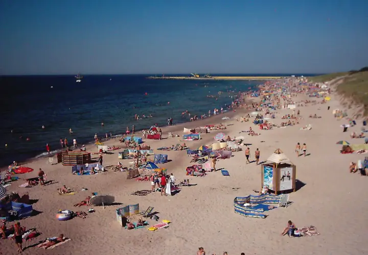 Tłum ludzi wypoczywa na plaży w Darłówku. Słońce, morze i piasek tworzą idealne warunki do relaksu.