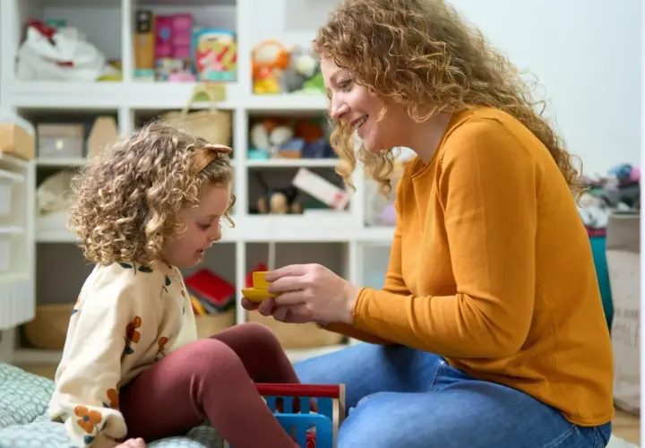 Mama z córką bawią się w pokoju pełnym zabawek. Czy urlop wychowawczy wlicza się do stażu pracy? To pytanie nurtuje wiele mam.
