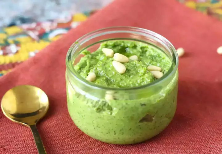 Un frasco de pesto casero, perfecto para tu próxima pasta al pesto receta, adornado con piñones.