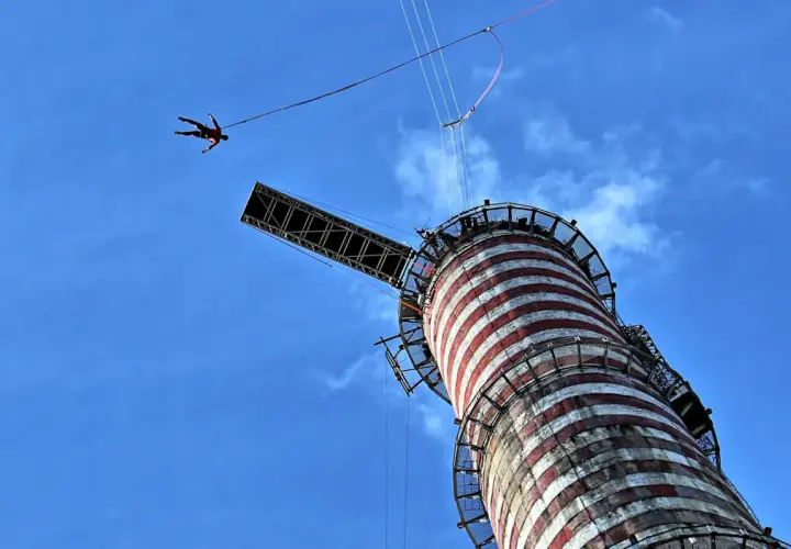 Osoba skacze na bungee z wieży, doświadczając adrenaliny. To najwyższe bungee w Polsce, oferujące niezapomniane wrażenia.