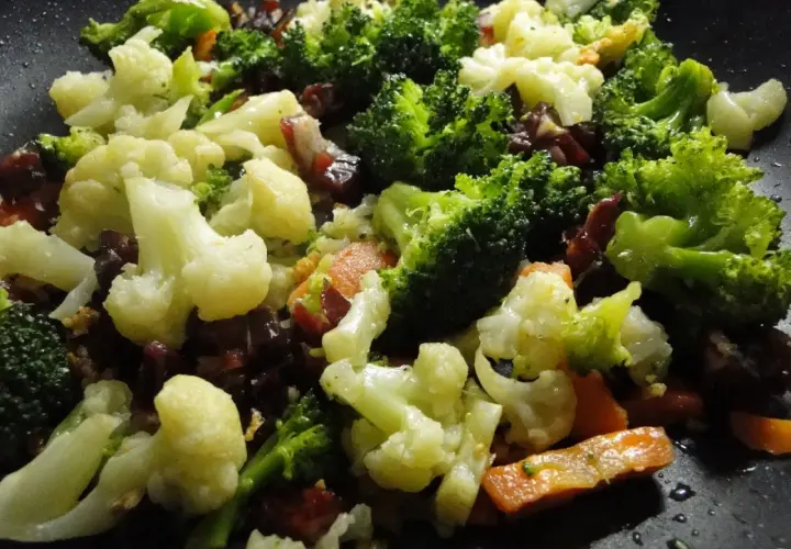 Un panache de verduras salteadas en sartén, con brócoli, coliflor y zanahoria, listo para disfrutar.