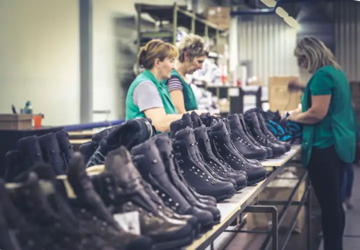 Workers inspect rows of Hanwag boots, hinting at where Hanwag boots are made: a factory floor.