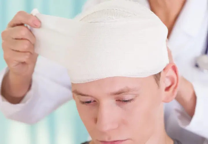 Lekarz opatruje głowę młodego mężczyzny, który doznał urazu aksonalnego.
