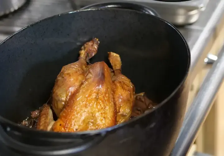 Un poulet rôti doré dans une cocotte. Quel vin rouge avec du poulet ? Un Pinot Noir léger ou un Beaujolais fruité serait parfait.