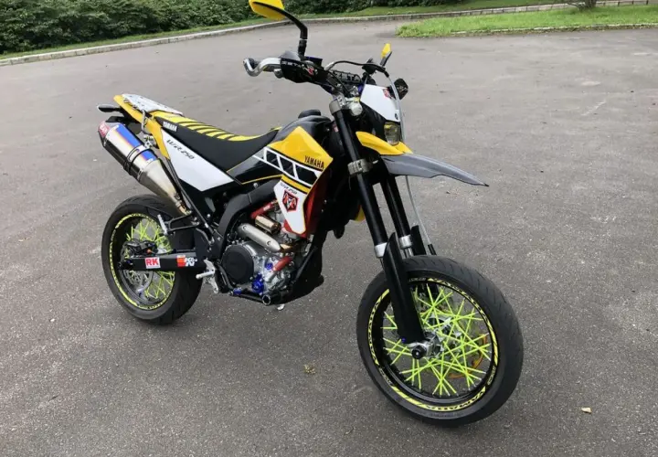 Yamaha WR 250 X personalizada con rines de radios amarillos brillantes y escape deportivo.