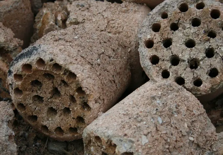 Brykiety z węgla brunatnego, gotowe do użycia. Pokazują, jak działa brykieciarka, sprasowując materiał w cylindryczne kształty z otworami.