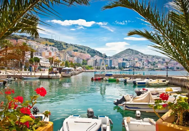 Albania, gdzie najpiękniej! Widok na port z łodziami i kolorowe budynki na wzgórzu.