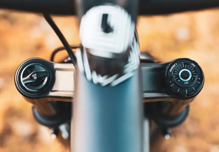 Close-up of a RockShox Pike fork's top caps, showing the "AIR" and "CHARGER 3" adjustments. The weight of this fork is a key factor for trail riders.
